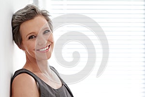 Complete job satisfaction. Portrait of a mature businesswoman leaning against a wall in her office.