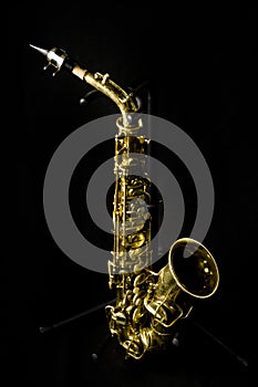 A complete view of a gold saxophone with mechanisms and buttons,
