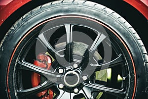 Completed in a high quality gloss. Black rim of luxury car wheel. Car wheel detail. Alloy wheel. Wheel and rim. Front or