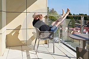 a completely relaxed vacationer sits on the balcony and enjoys the peace and the view