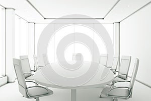 Completely white meeting room with a round table and large windows