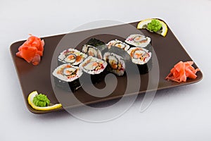 Complex roll - hot and cold with salmon, flying fish roe and avocado on white plate on black background