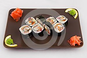 Complex roll - hot and cold with salmon, flying fish roe and avocado on white plate on black background