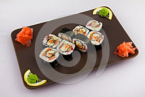 Complex roll - hot and cold with salmon, flying fish roe and avocado on white plate on black background