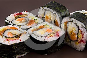 Complex roll - hot and cold with salmon, flying fish roe and avocado on white plate on black background