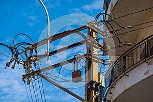 Complex web of power lines and transformers against clear blue sky