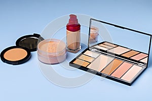 Complexion make up products and brush on blue background