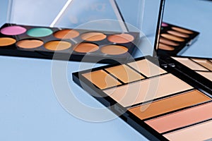 Complexion make up products and brush on blue background