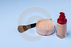 Complexion make up products and brush on blue background