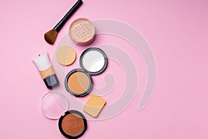 Complexion make up products and brush on pink background