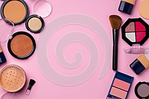 Complexion make up products and brush on pink background