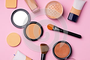 Complexion make up products and brush on pink background