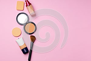 Complexion make up products and brush on pink background