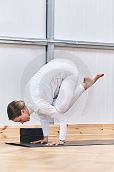 complicated inverted yoga asana. Crane posture Bakasana in Latin Caucasian woman