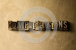 COMPLICATIONS - close-up of grungy vintage typeset word on metal backdrop