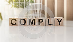 Comply word on wooden cubes on a light background