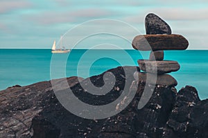 Composed rocks on shore with sailing ship