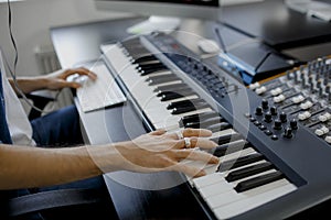 Composer hands on piano keys in recording studio. music production technology, man is working on pianino and computer