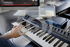 Composer hands on piano keys in recording studio. music production technology, man is working on pianino and computer