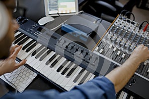 Composer hands on piano keys in recording studio. music production technology, man is working on pianino and computer