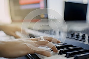 Composer hands on piano keys in recording studio. music production technology, man is working on pianino and computer