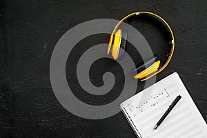 Composer office desk . Workplace of musician with headphones and notes black background top view mockup