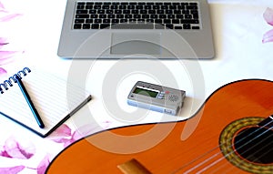 Composer`s work table. Top view of guitar, notepad, computer and tuner on the desktop