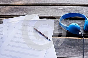 composing music with blue headphone and on the wooden desk
