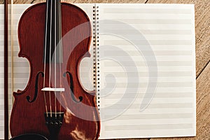 Composing for the violin. Top view of beautiful brown violin lying on sheets for music notes.