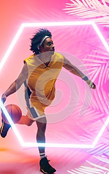 Composite of biracial basketball player dribbling ball by illuminated hexagon and plants, copy space