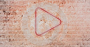 Composite of digital illuminated red play button icon against grunge brick wall, copy space
