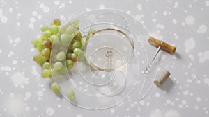 Composite of glass of white wine, grapes and corkscrew over vineyard background