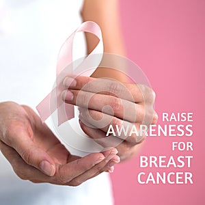 Composite of hands of caucasian woman holding pink ribbon and raise awareness for breast cancer text