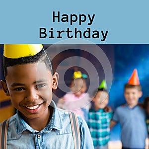 Composite of happy birthday text over happy african amercian boy in party hat at birthday party photo