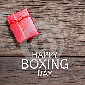 Composite of happy boxing day text over red gift box on wooden table