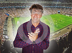 Composite with happy and excited soccer fan man and football pitch background celebrating his team scoring and winning in sport