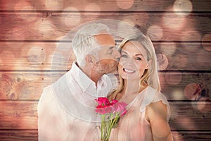 Composite image of affectionate man kissing his wife on the cheek with roses