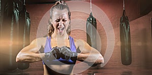 Composite image of aggressive female boxer flexing muscles