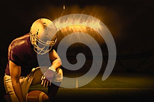 Composite image of american football player kneeling while holding ball