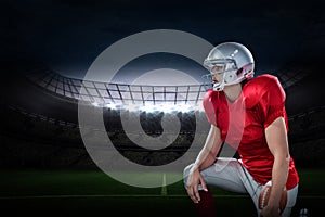 Composite image of american football player looking away while kneeling