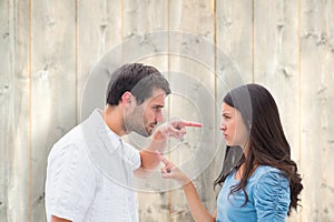 Composite image of angry couple pointing at each other
