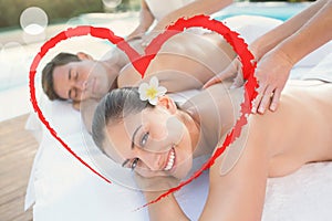 Composite image of attractive couple enjoying couples massage poolside