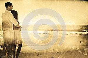 Composite image of attractive couple looking out at sea