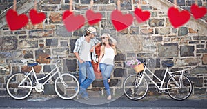 Composite image of attractive couple standing with bikes