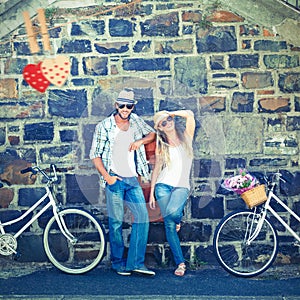 Composite image of attractive couple standing with bikes