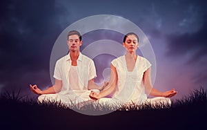 Composite image of attractive couple in white meditating in lotus pose