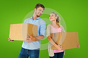 Composite image of attractive young couple carrying moving boxes