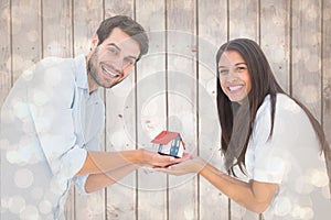 Composite image of attractive young couple holding a model house