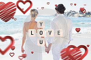 Composite image of bride and groom holding hands looking out to sea
