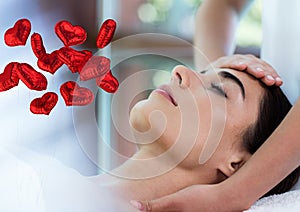 Composite image of bunch of red heart shaped foil balloons against woman receiving a head massage